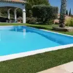 Maison blanche avec piscine, pelouse artificielle et palmier